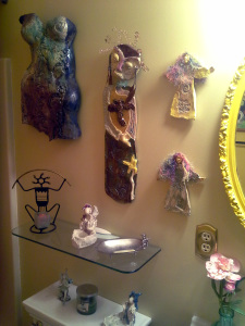 my raku torso, bird woman and wylde women on the wall, and one of my fairy candle holders on the glass shelf